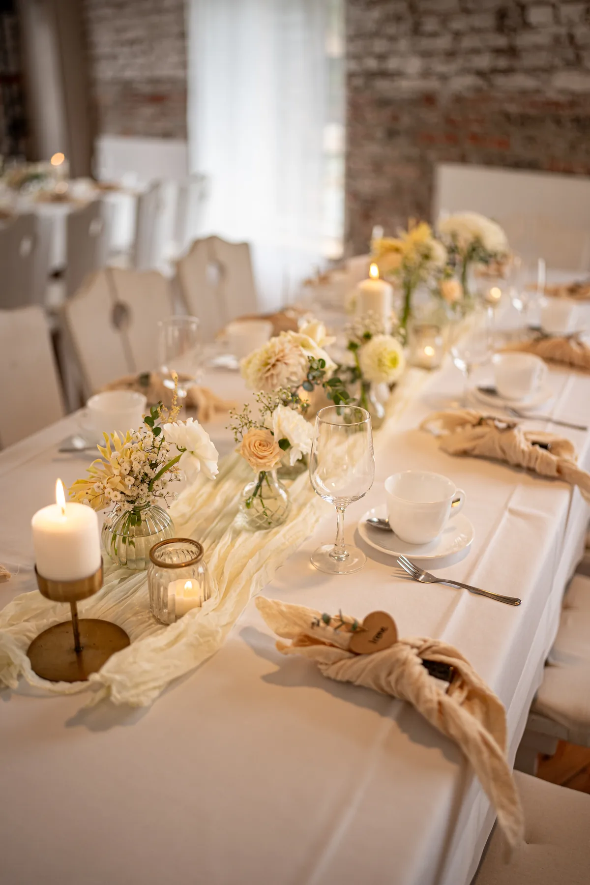 Festlich gedeckte Tafel mit Kerzen und hellen Blumen