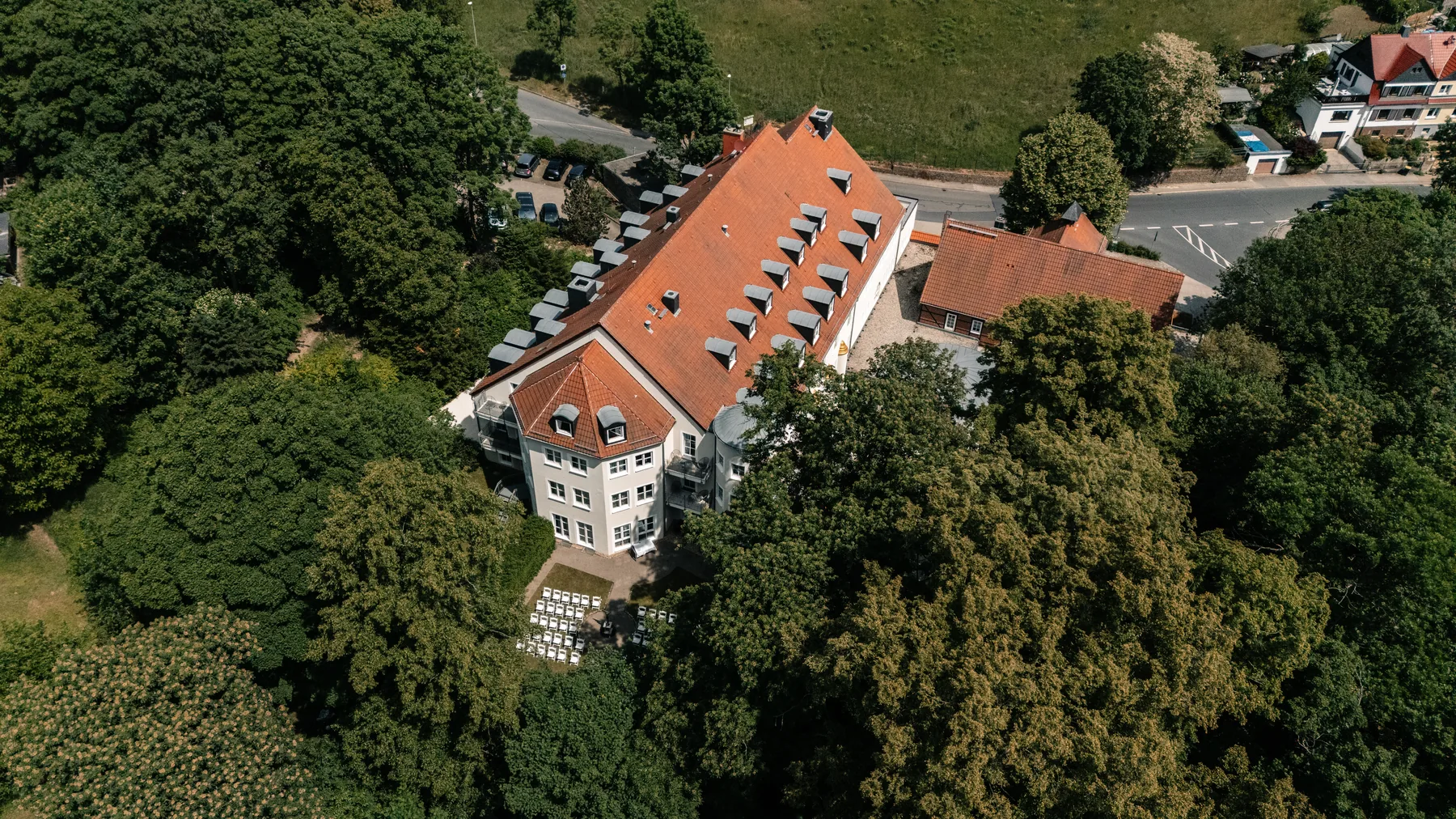 Hotel und Eventlocation aus der Luft, umgeben von altem Baumbestand