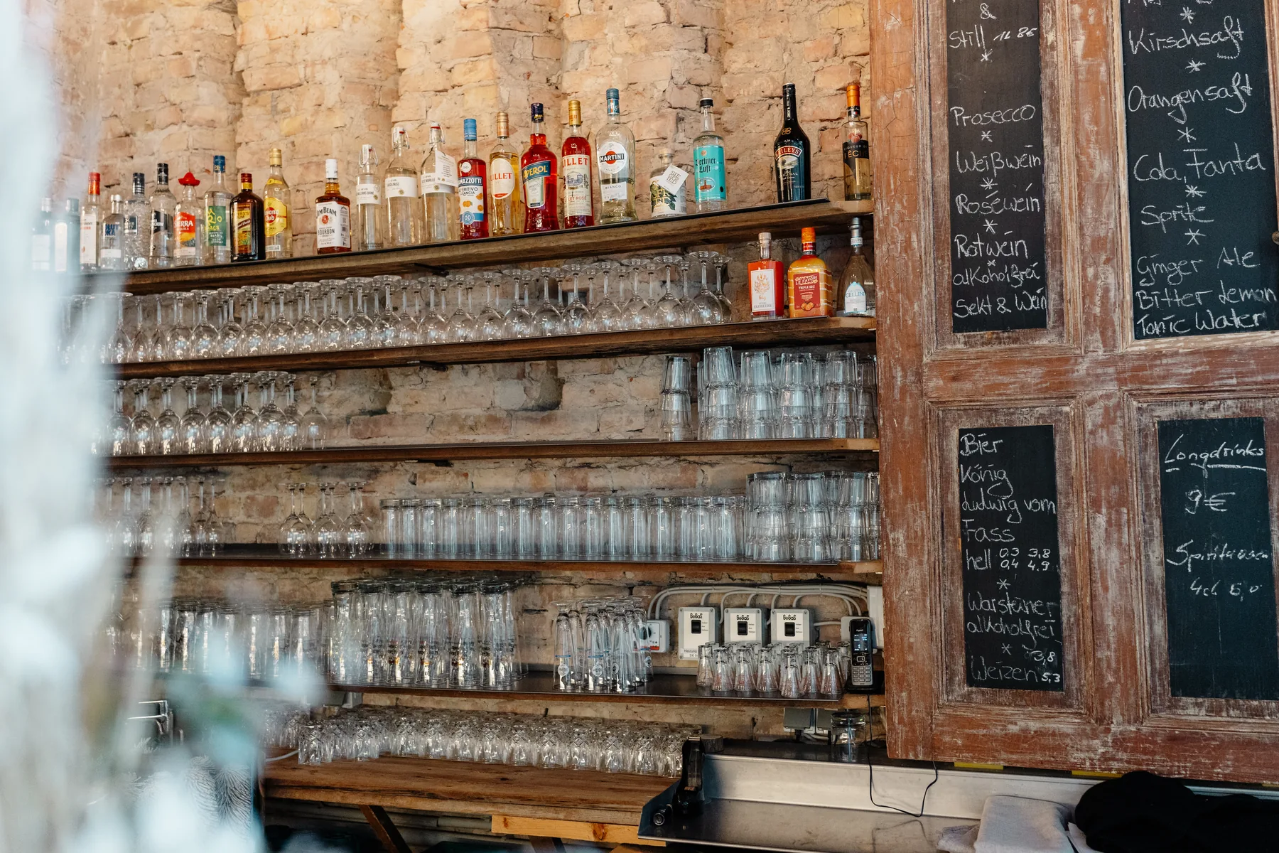 Gut ausgestattete Bar vor einer historischen Ziegelwand