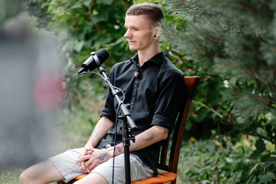 Gesprächspartner von JFG Immobilien sitzt vor einem Mikrofon im Garten