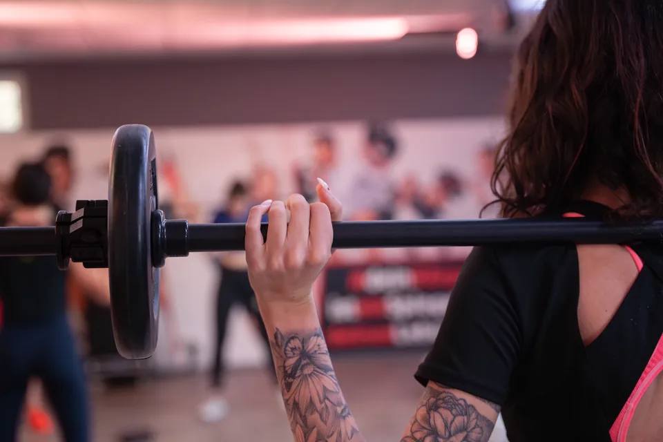 Teilnehmerin hält eine Langhantel beim gemeinsamen Kurs im MC Shape