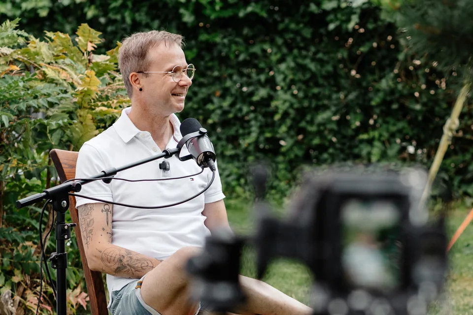 Gesprächspartner mit Mikrofon und Kamera bei einer Podcast-Aufnahme im Freien