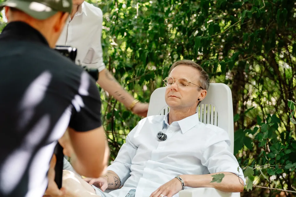 Toni filmt einen sitzenden Gesprächspartner im Garten