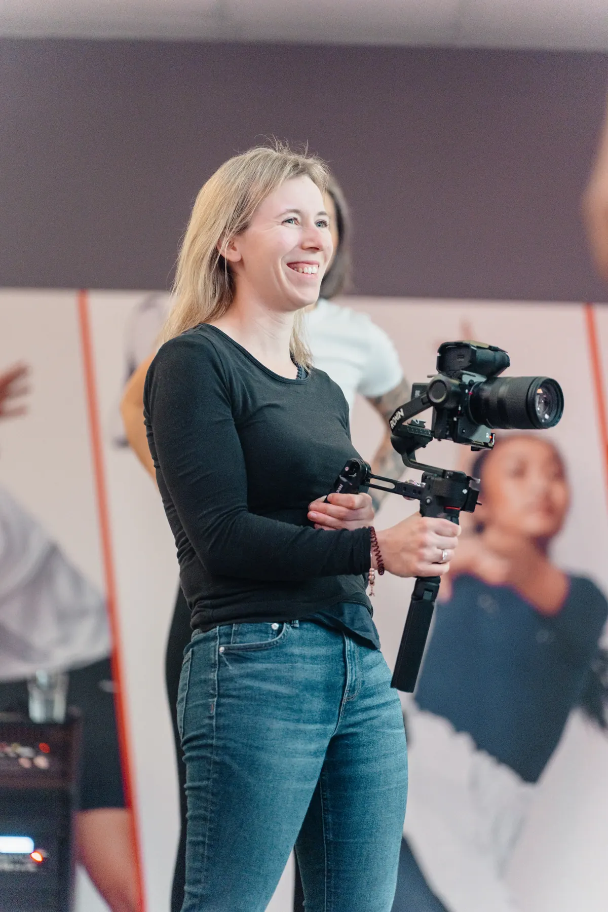 Anne mit Kamera und Gimbal während einer Videoproduktion im Fitnessstudio