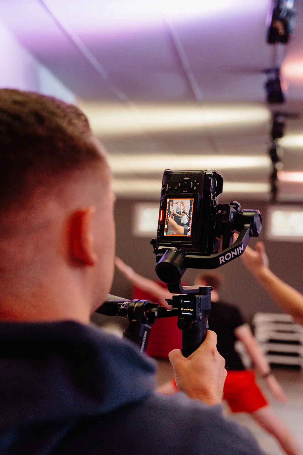 Toni kontrolliert das Kameradisplay beim Filmen eines Fitnesskurses