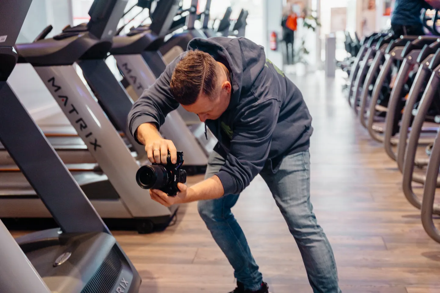 Toni filmt mit seiner Kamera zwischen den Geräten eines Fitnessstudios